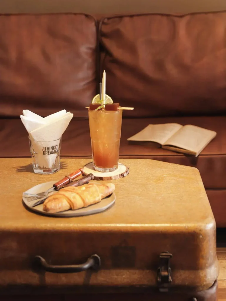 Verre de mocktail original posé sur une table en bois, boisson créative inspirée de mondes imaginaires au café de l'imaginaire Je(u) Rêve à Brest