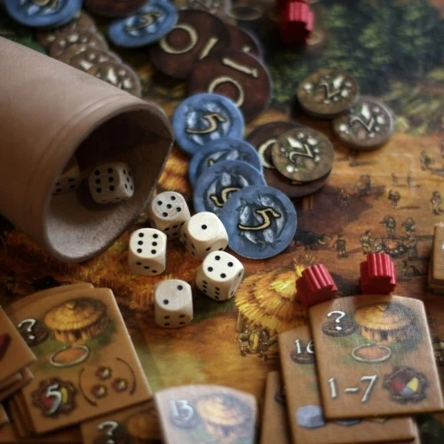 un plateau de jeu avec des pions, des dés et un gobelet en cuir