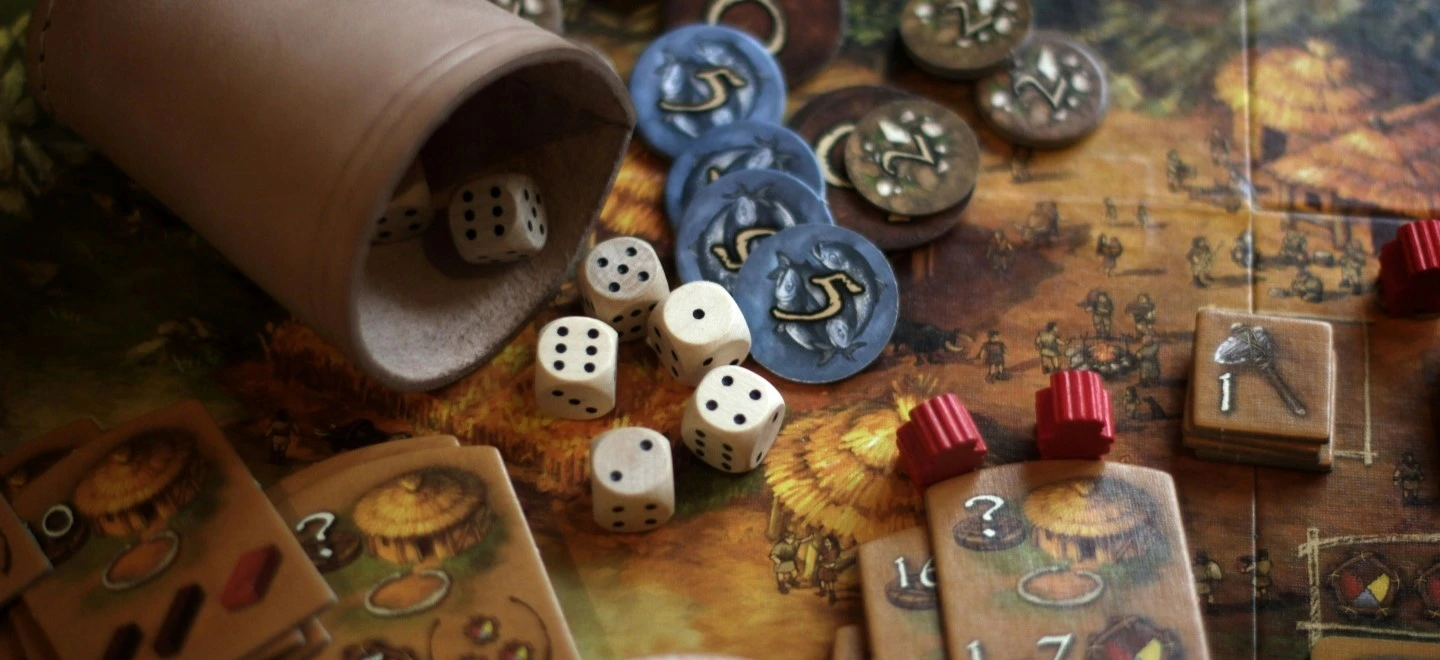 un plateau de jeu avec des pions, des dés et un gobelet en cuir